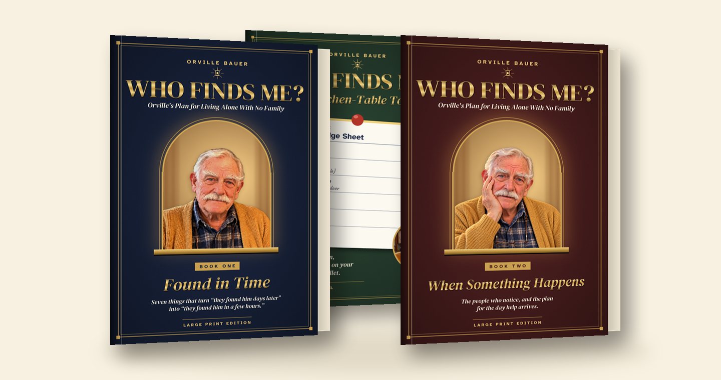 The three books standing together: Book One in navy, Book Two in deep red, and the green Kitchen-Table Toolkit behind them.